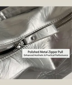 Detail of silver metallic crescent bag showing smooth hardware zipper and leather puller