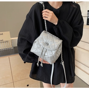 Detail eines silbernen gesteppten Rucksacks mit Kettenriemen und Metall-Drehverschluss