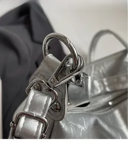 Close-up of polished silver hardware hook and wrinkled texture on a metallic tote bag