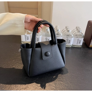 Nahaufnahme der schwarzen Handtasche aus Leder mit Litschistruktur und Klappverschluss