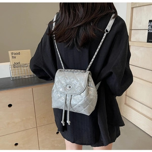 Detail eines silbernen gesteppten Mini-Rucksacks mit Kettenriemen und Drehverschluss