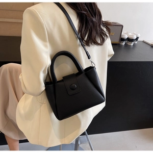 Détail du sac seau noir en cuir grainé avec poignée supérieure et fermeture à rabat