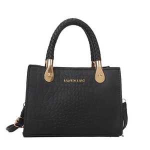 Black crocodile embossed handbag with woven handle and gold fashion lettering on white background