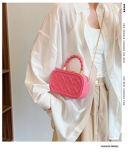 Detalle de bolso cuadrado rojo rosa con relieve floral y asa superior trenzada