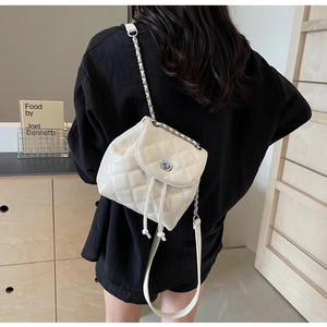 Detail eines weißen gesteppten Mini-Rucksacks aus Lackleder mit silberner Kette