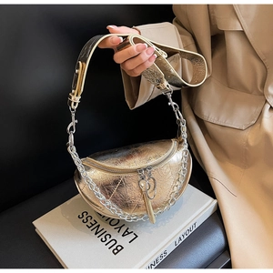 Detail of champagne gold dumpling bag with crinkle texture and silver chain strap