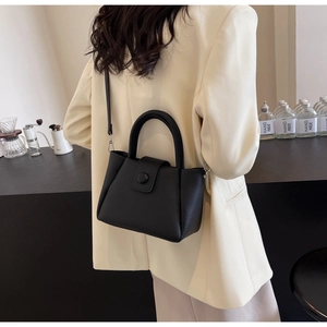 Détail du sac à main en cuir grainé noir avec boucle ronde et fermeture magnétique