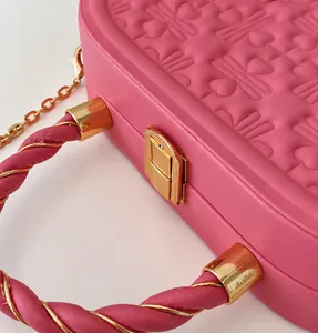 Detalle de bolso rosa en cuero PU con relieve de corazón y cierre de hebilla metálica
