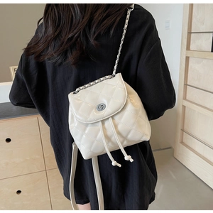 Gesteppter cremeweißer Mini-Rucksack mit silberner Kette am Rücken eines Models