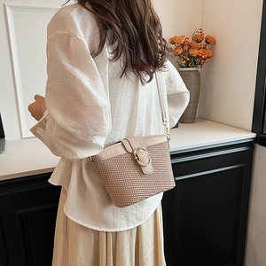 Minimalist beige woven crossbody bag with round gold buckle and smooth leather strap