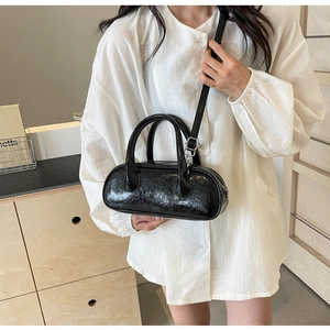 Detail of black glossy oil wax leather bowling bag with silver hardware and shoulder strap