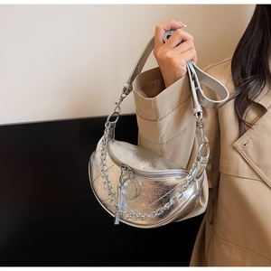 Silver metallic dumpling bag with chain detail worn over a khaki trench coat