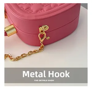 Detalle del bolso rosa de corazón con gancho metálico dorado y cadena de metal