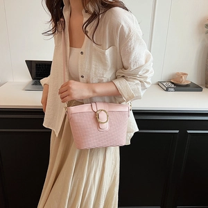Pink woven crossbody bag with gold round buckle shown on model in casual style