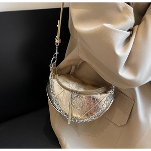 Detail of metallic gold half-moon bag featuring pleated texture and silver chain strap