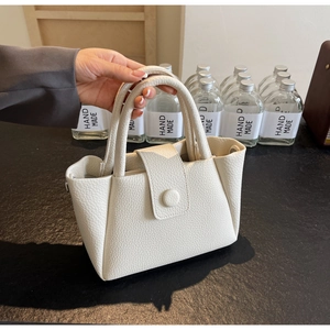 Nahaufnahme der weißen Handtasche aus strukturiertem Leder mit runden Metallverschluss