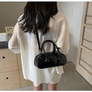 Rear view of model wearing a black glossy bowling bag with slender shoulder strap