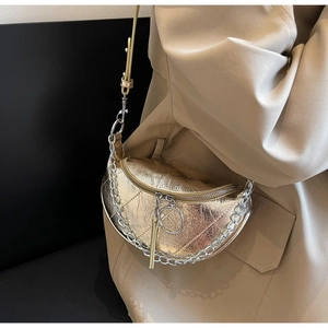 Macro detail of golden metallic dumpling bag with quilted texture and chain strap