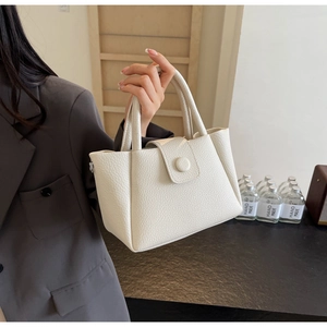 Détail du sac à main blanc à motif litchi avec boucle décorative ronde élégante