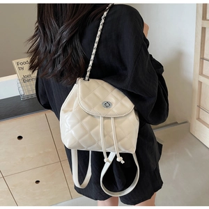 Detail des gesteppten beigen Rucksacks mit Metallketten und Drehverschluss-Design