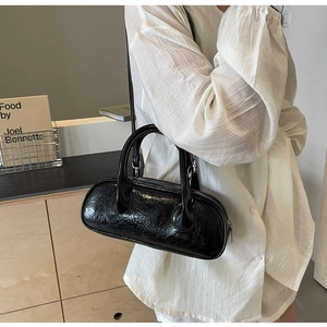 Detail view of the black cylindrical bowling bag with glossy textured leather and zip closure
