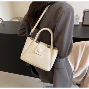 Détail macro du sac seau en cuir grainé blanc crème avec des finitions en métal argenté
