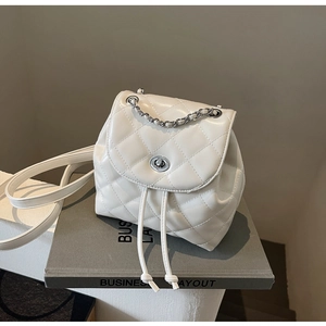 Nahaufnahme der cremefarbenen Mini-Rucksacktasche mit Steppmuster und Ketten-Detail