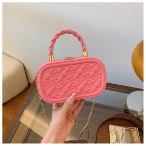 Detalle de bolso caja ovalado rosa con patrón de corazones y cadena dorada