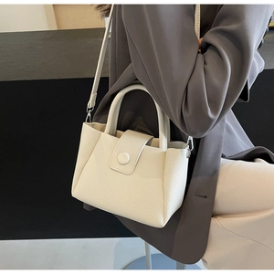 Vue détaillée du sac à main en cuir crème avec fermoir doré et poignée supérieure
