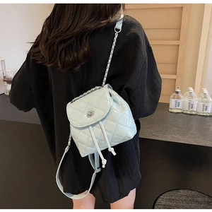 Detail eines mintgrünen gesteppten Mini-Rucksacks mit Glanzeffekt und Kettenriemen am Model
