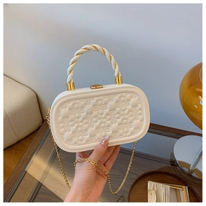 Primer plano de bolso caja acolchado blanco con asa trenzada y cadena dorada de hombro