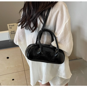 Glossy black bowling bag shown on a model wearing a white shirt for a modern look