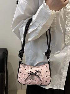 Sac à bandoulière rose avec nœuds noirs et breloque cœur porté par un mannequin doux