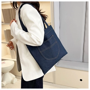 Detail of dark blue denim tote bag with decorative pocket and contrast stitching