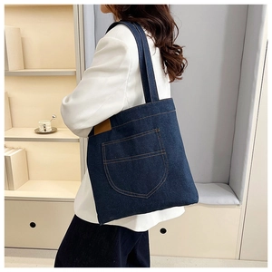 Detailed side view of large capacity denim tote bag with decorative pocket and shoulder straps