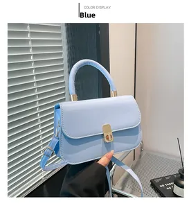 Detailed shot of light blue square crossbody bag with metallic lock and matte leather finish