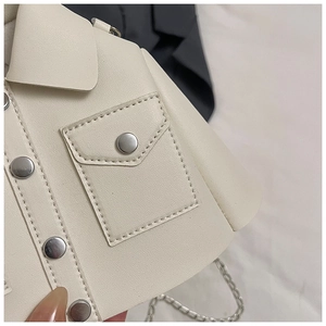 Detail of creative cream jacket-shaped handbag featuring metal snaps and silver chain strap