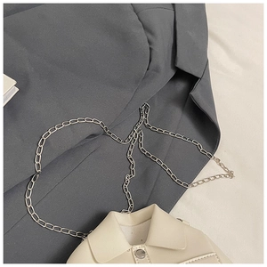 Detail of cream beige chain bag featuring suit lapel design and silver button on grey blazer