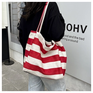 Close-up of a large capacity red and white striped canvas tote bag in a street style view