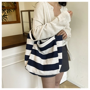 Detailed view of large blue and white striped canvas tote bag on a model in a cozy room