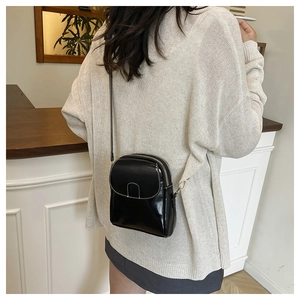 Crossbody phone bag in black leather with white contrast stitching on model