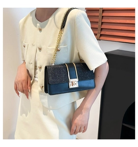 Detail of black sequined crossbody bag with gold twist lock and elegant chain strap