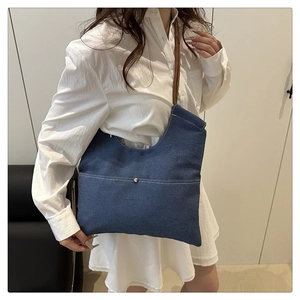 Close-up of dark blue denim tote bag with white contrast stitching and rope shoulder strap