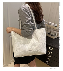 Close-up of white woven tote bag with fashion plaque and slim shoulder strap