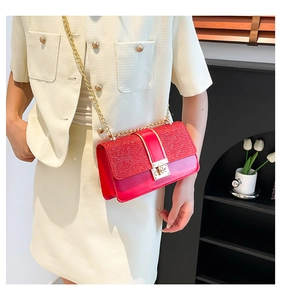 Close-up of bright red sequined shoulder bag with gold metal lock and chain strap detail