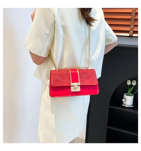 Model wearing a vibrant red sequin crossbody bag with gold chain strap and metal lock