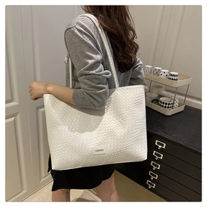 Gros plan d'un sac cabas tressé blanc avec étiquette FASHION porté par un mannequin