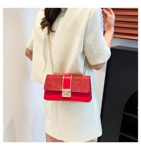 Detail of red sequin flap handbag with gold lock on female model in modern setting