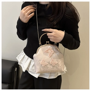 Detail of floral jacquard fabric and pink butterfly embroidery on a vintage style handbag