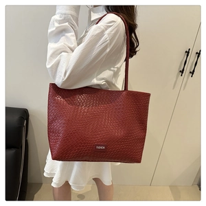 Détail du cabas tressé rouge avec une étiquette Fashion blanche sur le devant inférieur